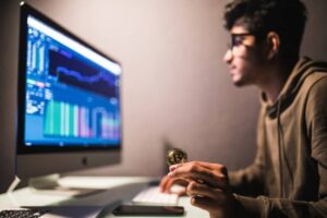 Man Holds Coin and Works on the Computer