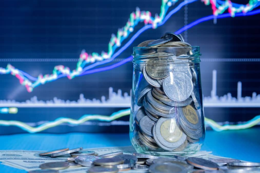 A jar of coins against a backdrop of financial growth charts