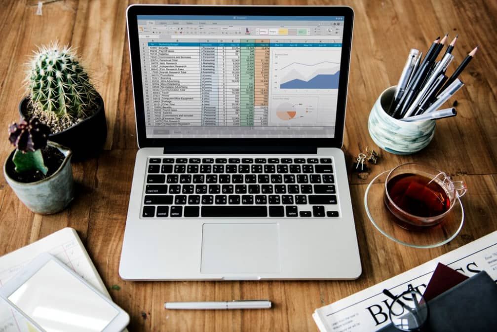  A laptop displaying a spreadsheet surrounded by office supplies