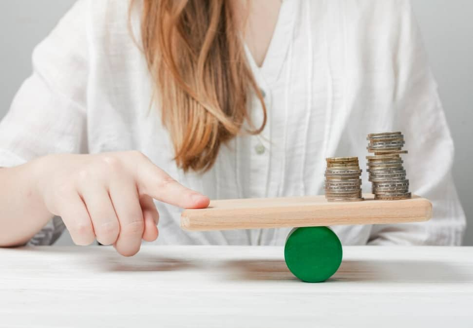 Woman balancing coins on a seesaw, symbolizing financial stability